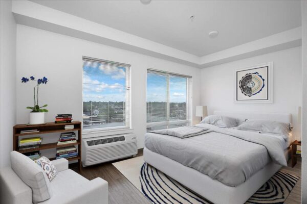 The Overland apartment bedroom with plush bed, shelves with books, and large windows.