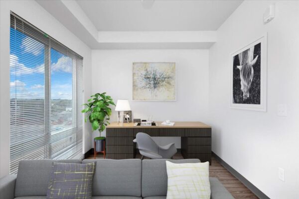 The Overland apartment living area with plush seating, desk, wall art, and large windows.