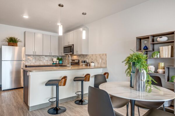 The Overland apartment kitchen with wood style floor, dining table, and stainless steel appliances.