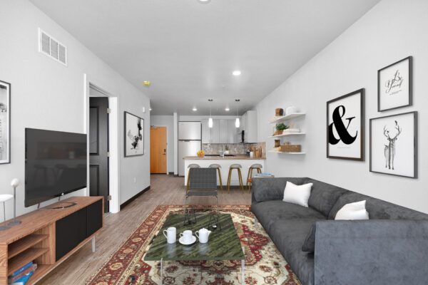 The Overland apartment living room with plush seating, console with TV, and wall art.
