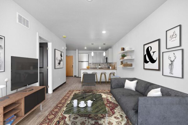 The Overland apartment living room with wood style floor, plush seating, framed artwork, and TV.