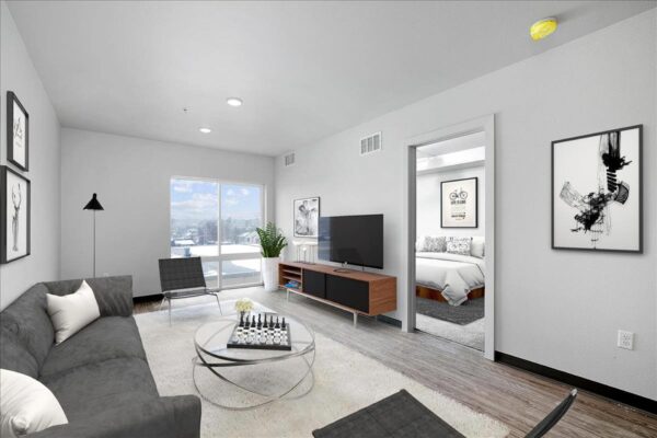 The Overland apartment living room with plush seating, console with TV, and large windows.