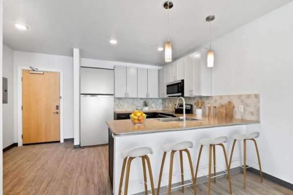 The Overland apartment kitchen with wood style floor, two tone cabinets, and stainless steel appliances.