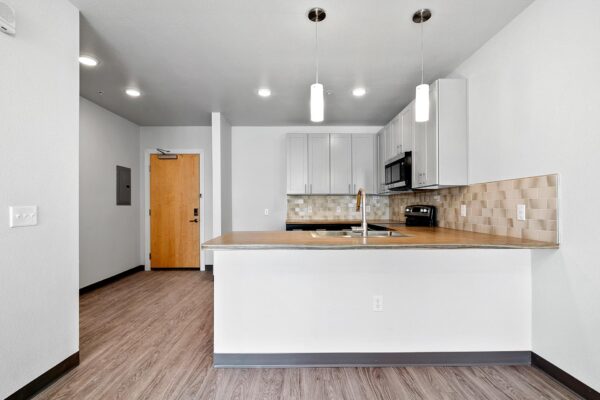 The Overland apartment kitchen with wood style floor and two tone cabinets.