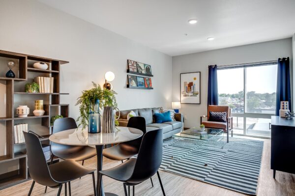 The Overland apartment living room with dining table, plush seating, and large windows.