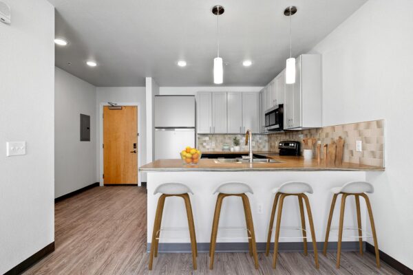The Overland apartment kitchen with wood style floor, two tone cabinets, and stainless steel appliances.