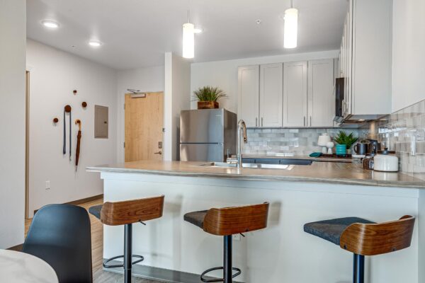 The Overland apartment kitchen with two tone cabinets, stainless steel appliances, and bar stools.