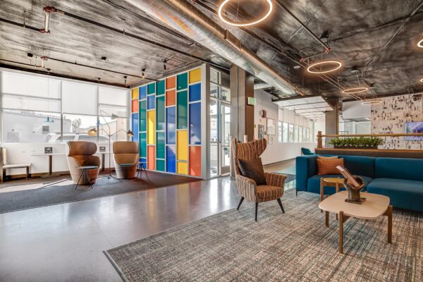The Overland apartments lounge with plush seating, colorful wall, and industrial styling.