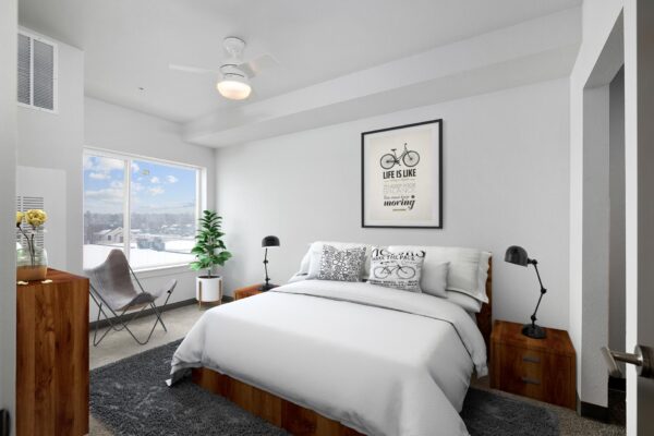 The Overland apartment bedroom with plush bed, framed artwork, and large windows.