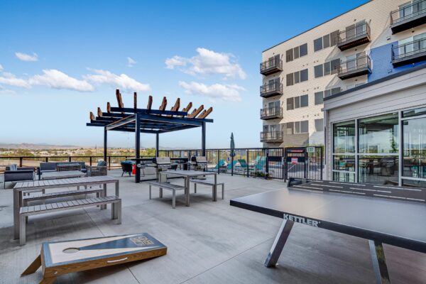 The Overland apartments rooftop deck with table tennis, bag toss, and dining tables.