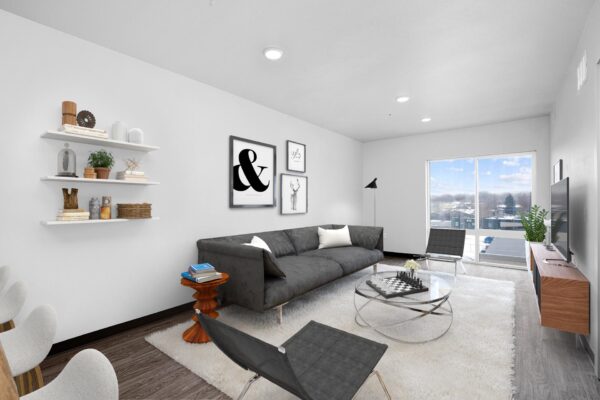 The Overland apartment living room with plush seating, shelves with decor, and large windows.