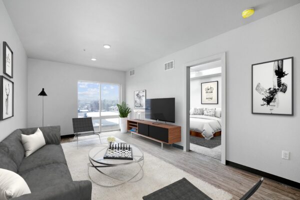 The Overland apartment living room with plush seating, console with TV, and large windows.