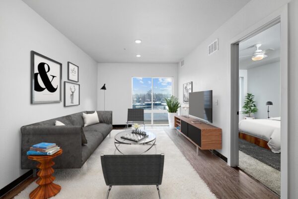 The Overland apartment living room with plush seating, console with TV, and large windows.