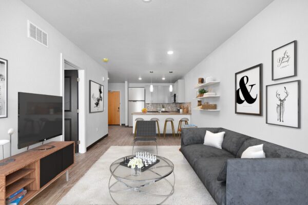 The Overland apartment living room with plush seating, console with TV, and wall art.