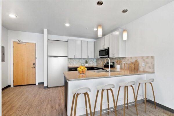 The Overland apartment kitchen with wood style floor, two tone cabinets, and stainless steel appliances.
