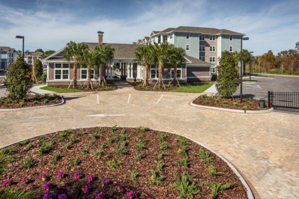 The Point at Bella Grove apartments leasing office exterior with parking lot with palm trees.
