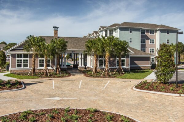 The Point at Bella Grove apartments leasing office exterior with parking lot with palm trees.