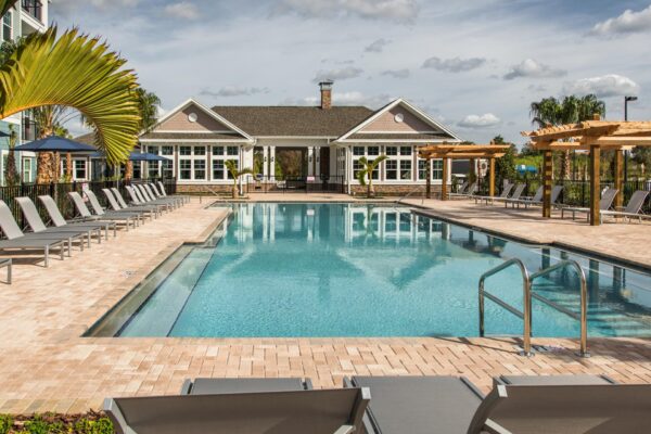 The Point at Bella Grove apartments pool area with lounge chairs, metal fencing, gazebo and palm trees.