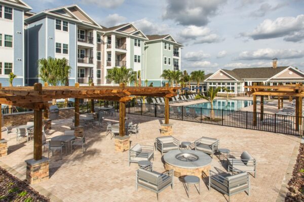 The Point at Bella Grove apartments outdoor lounge area with firepit, grilling stations next to pool area.