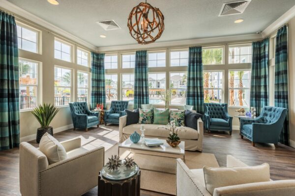 The Point at Bella Grove apartments clubroom with plush seating, large windows, and ceiling to floor curtains.