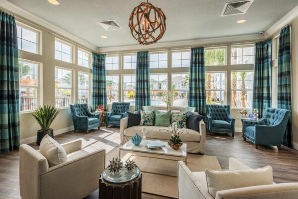 The Point at Bella Grove apartments clubroom with plush seating, large windows, and ceiling to floor curtains.