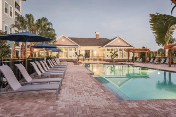 The Point at Bella Grove apartments pool area with lounge chairs, metal fencing, gazebo and palm trees.