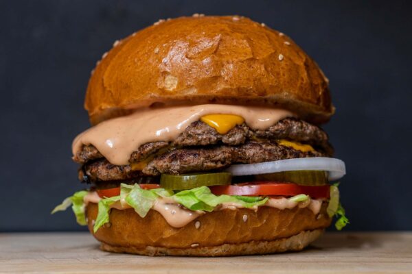 Double cheeseburger with lettuce, tomato, pickles, and sauce.
