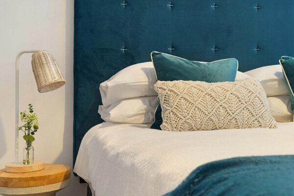 Bedroom with plush bedding, soft headboard, and bedside table with lamp.