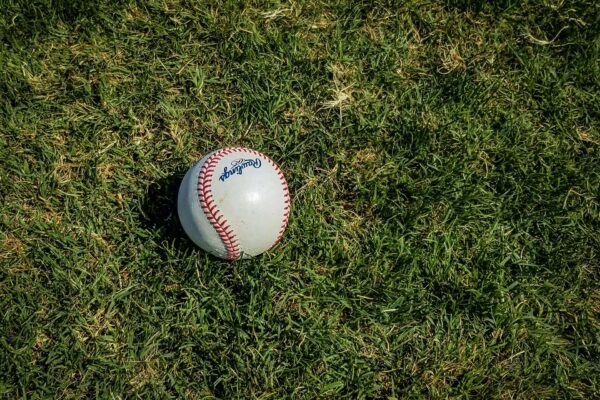 Baseball lying on green grassy field.