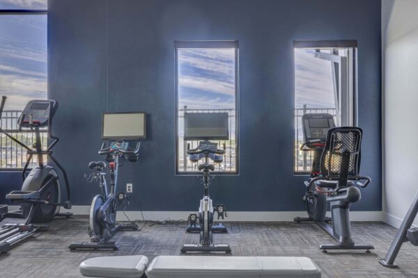 Copper 87 apartments fitness center with cardio machines and large windows.