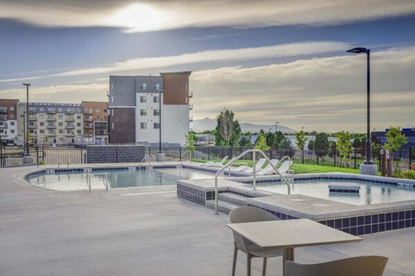 Copper 87 apartments pool area with lounge chairs, hot tub, and dining tables.