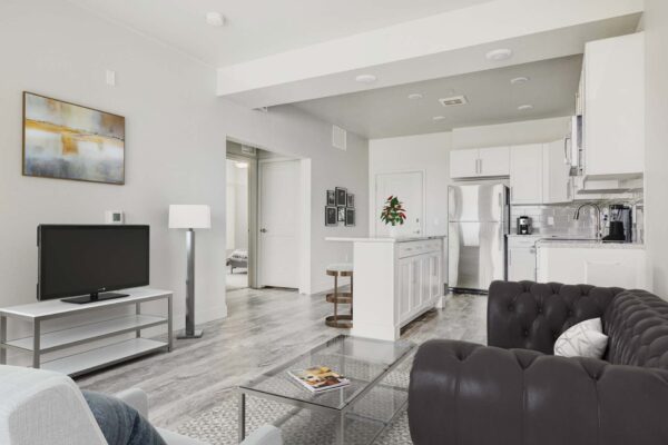 Copper 87 apartments living room with plush seating, TV, framed artwork, and modern kitchen.