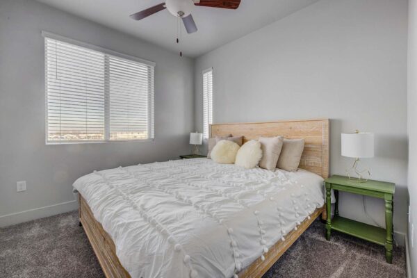 Copper 87 apartments bedroom with carpet, bed with headboard, and bedside tables with lamps.