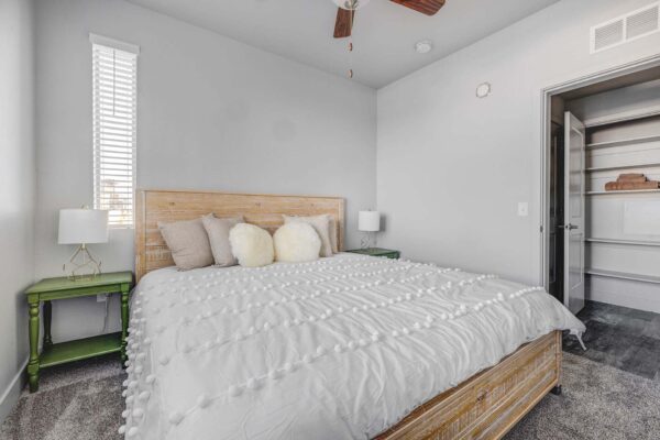 Copper 87 apartments with plush carpet, bed with headboard, bedside tables with lamps, and ceiling fan.