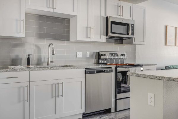 Copper 87 apartments kitchen with white cabinets, stone counters, and stainless steel appliances.