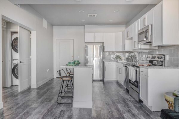 Copper 87 apartments kitchen with wood style floor, white cabinets, stone counters, and stainless steel appliances.