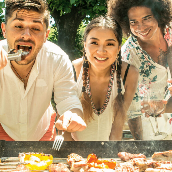 Friends laughing together over a BBQ grill.