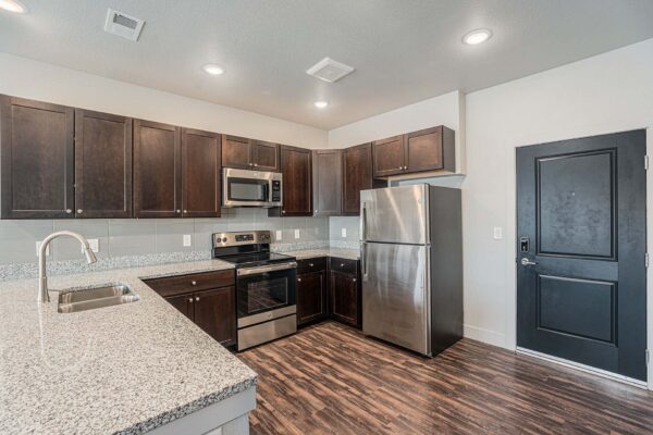 The Marc at Monument Ridge apartment kitchen with wood cabinets and stone counters.