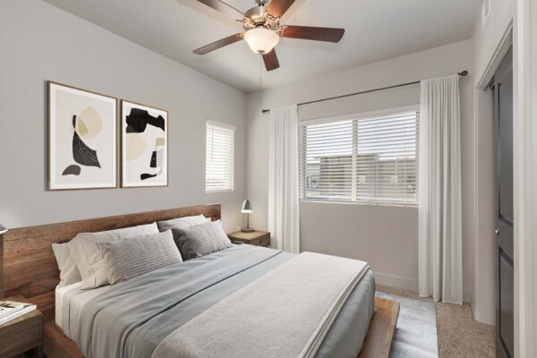 The Marc at Monument Ridge apartment bedroom with plush bed, bedside tables with lamps, and ceiling fan.