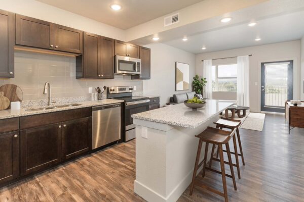 The Marc at Monument Ridge apartment kitchen with wood style floor, island, and stainless steel appliances.