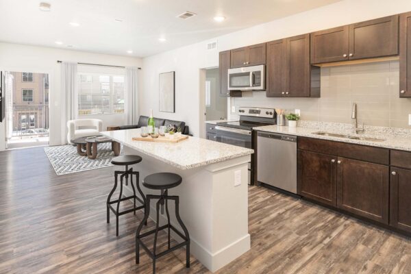 The Marc at Monument Ridge apartment kitchen with wood style floor, island, and stainless steel appliances.