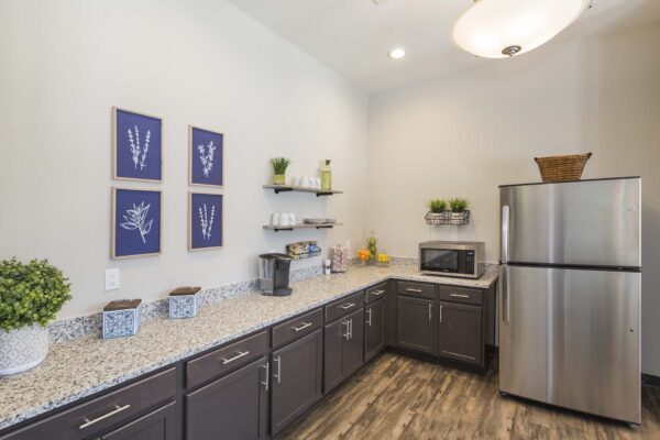 The Retreat at Patriot Park community kitchen with wood cabinets, granite counters, and stainless steel appliances.