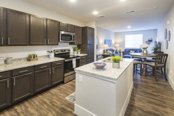 Retreat at Patriot Park apartment kitchen with wood style floor, wood cabinets, granite counters, and stainless steel appliances.