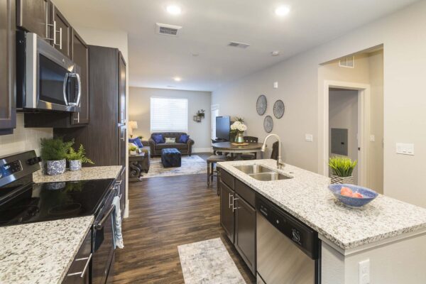 Retreat at Patriot Park apartment kitchen with wood style floor, wood cabinets, granite counters, and stainless steel appliances.
