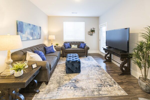 The Retreat at Patriot Park apartment living area with plush seating, elegant decor, and balcony door.