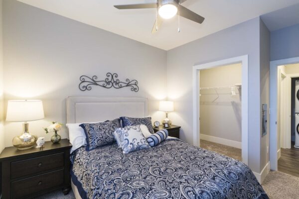The Retreat at Patriot Park apartment bedroom with plush bed, bedside tables with lamps, and large closet.