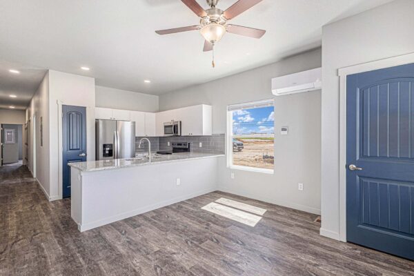 The Cottages at Woodmen Heights apartment living area with wood style floor, modern kitchen, and large windows.