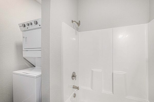 The Cottages at Woodmen Heights apartment bathroom with shower tub and washer dryer.