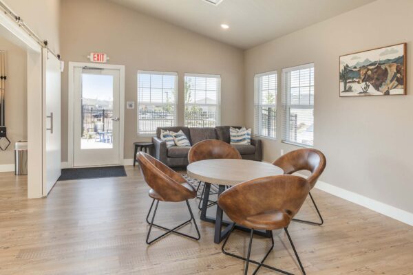 Cottages at Woodmen Heights apartment clubroom with dining table and plush couch.