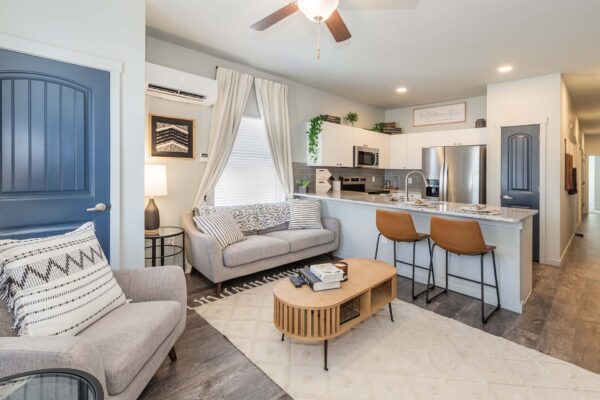 Cottages at Woodmen Heights apartment living room with plush seating, coffee table, and breakfast bar.
